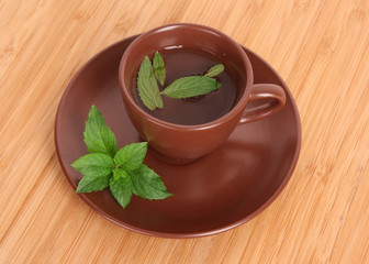 Cup of green tea on the saucer with mint on wooden surface