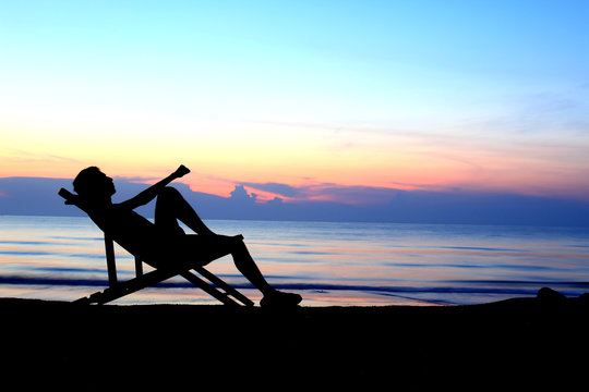 deckchairs and man on beach at sunset .