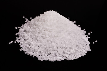 White crystal sugar pile isolated over black background.