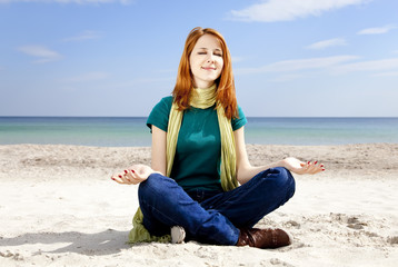 Fototapeta na wymiar Young beautiful red-haired girl at the beach in spring time.