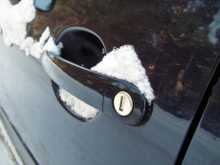 Schnee auf Türgriff von blauem Auto 