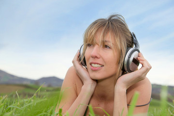 Beautiful woman in green field with headphones on
