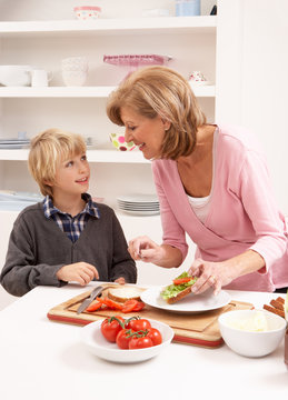 Grandmother And Grandson Making Sandwich In Kitchen