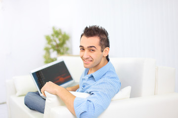 Happy man working on his laptop on the sofa at home