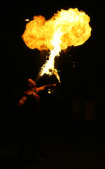 Fire breathing street performance artist at night.