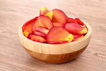 Rose petals in bowl on wooden background