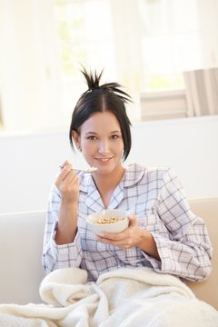 Portrait of woman having cereal on sofa