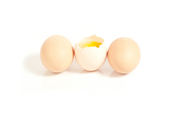 Three eggs standing, one cracked On white background