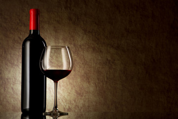 bottle with red wine and glass on a old stone
