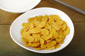 Cornflakes in bowl  on wood background