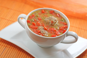 Home-made meatballs and vegetable soup, in a white soup cup