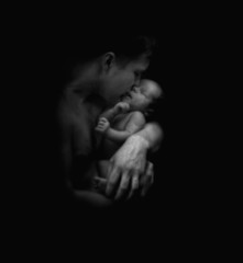 Father hugging a newborn baby, b/w