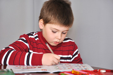 A boy in a red sweater makes lessons at home