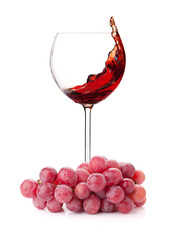 Splashing red wine in a glass and grapes