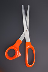 Orange scissors on the black background