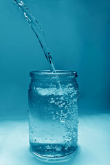 water flows into a glass jar forming bubbles and drops