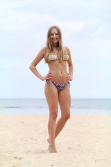 Young woman standing on a beach and enjoying the sun