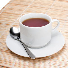 Cup of black tea with spoon on napkin isolated