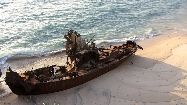 Rusty stranded boat lying in a desert beach