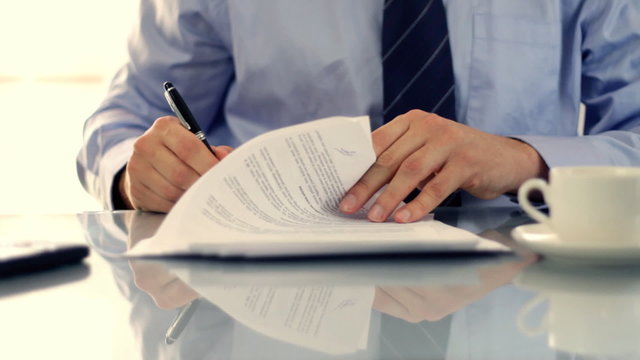 Businessman signing documents on reflective table