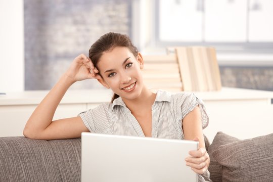 Young woman using laptop at home smiling