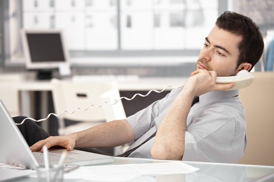 Young male sitting at desk talking on phone