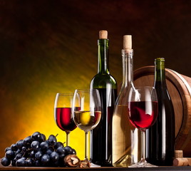 Still life with wine bottles, glasses and oak barrels.
