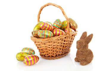 Cane basket with colorful easter eggs over white background