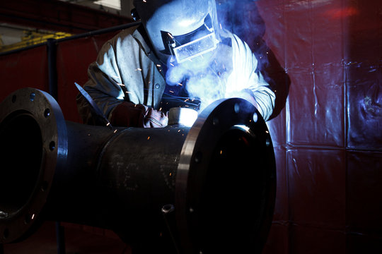 worker weld metal in factory and sparks