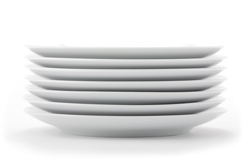 Stacked white dishes on seamless white background.