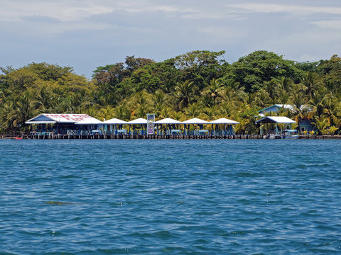 Tropical restaurant bar with kiosks over the sea and lush vegetation behind, Carenero island, Bocas del Toro, Panama, Central America