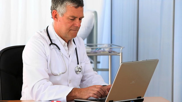 Senior doctor  working on his laptop