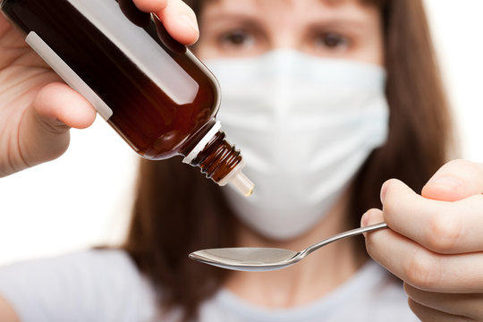 Doctor in mask holding medicine syrup