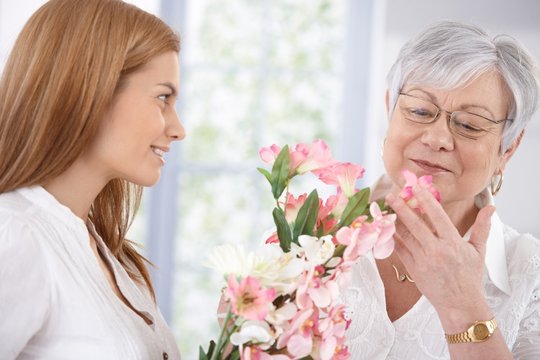 Pretty woman greeting mother with flowers smiling