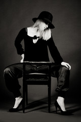 Provocative sexy blonde woman with hat sitting on a chair