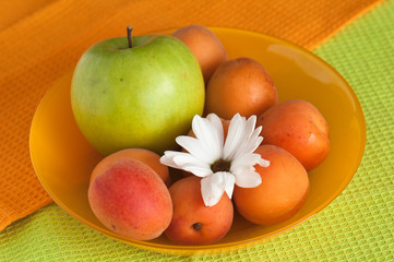 The ripe apricot and green apple lays on towels