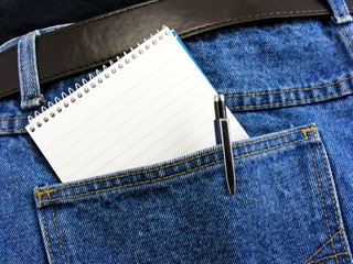 A notebook & pen in dark denim jeans back pocket