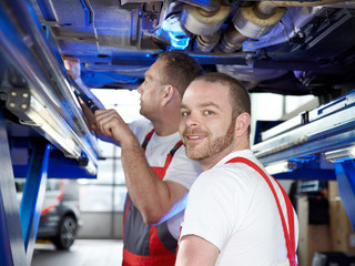 Motorcar mechanics inspecting  the engine of a car in a garage