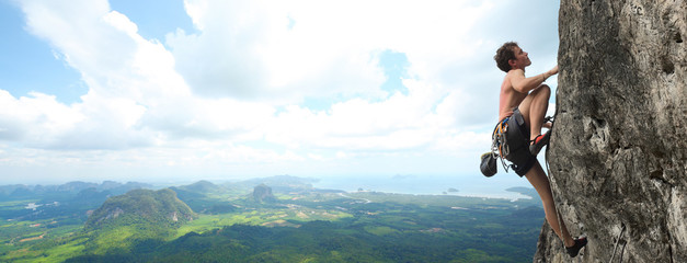 Young male climbing on a cliff on wide alley background © Dudarev Mikhail