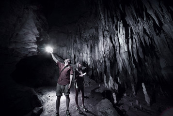 Young couple exploring huge cave with torches