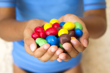 Bonbons colorés au chocolat dans les mains d'un enfant