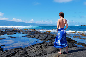 Girl on the Maui beach standing on the lava rocks.