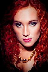 Fototapeta premium girl with red curly hair wearing amber necklace on black
