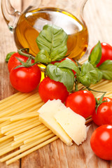 pasta, olive oil and tomatoes on the wood background