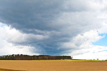 dark clouds and blue sky over fields