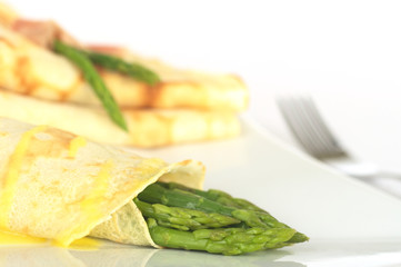 Green asparagus wrapped in crepes with sauce