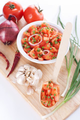 Salsa in a bowl on a wooden board and ingredients