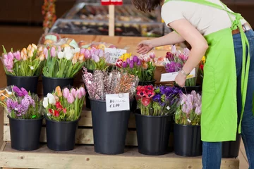 Selbstklebende Fototapete Blumenladen verkäuferin ordnet blumen im supermarkt