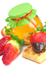 big juicy ripe strawberries in chocolate, a jar of honey and waf