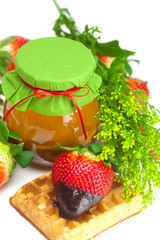 big juicy ripe strawberries in chocolate, a jar of honey and waf